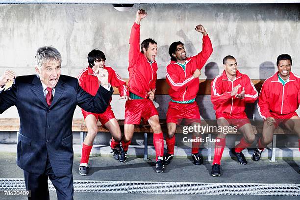 coach and soccer team on bench cheering - banco de jogadores fotografías e imágenes de stock