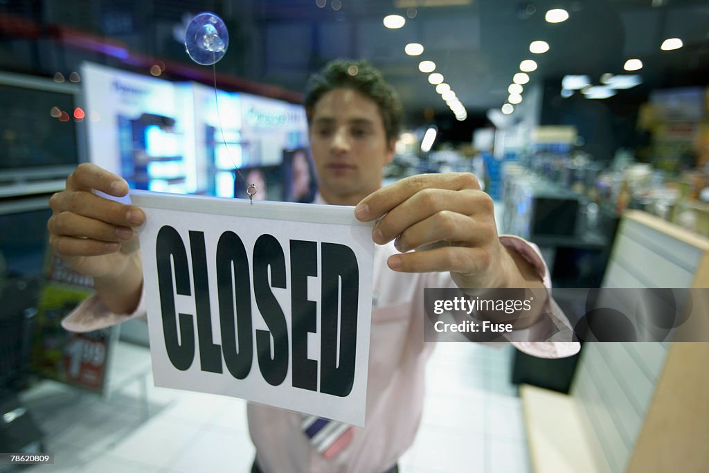 Man Hanging Closed Sign on Door