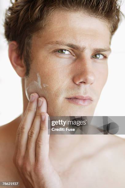 man applying facial cream - hombre crema facial fotografías e imágenes de stock