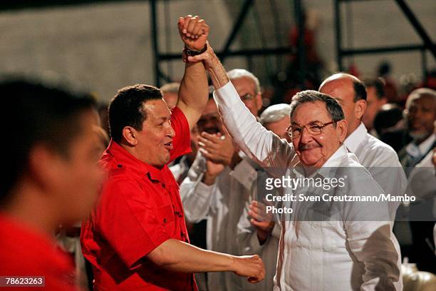 Acting President of Cuba Raul Castro raises the arm of President of Venezuela Hugo Chavez during the closing session of the 4th PetroCaribe Summit in...