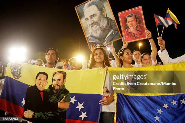 Students from Venezuela hold Venezuelan flags and images of President of Cuba Fidel Castro and President of Venezuela Hugo Chavez during the closing...