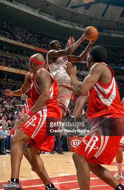 Luol Deng of the Chicago Bulls goes to the basket past Bonzi Wells and Aaron Brooks of the Houston Rockets on December 22, 2007 at the United Center...