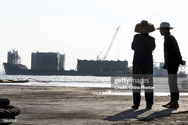 Fishermen watch as a barge carrying the wreck of the 800-year-old sunken merchant ship "Nanhai No.1" , berth at a dock of the "Marine Silk Road...