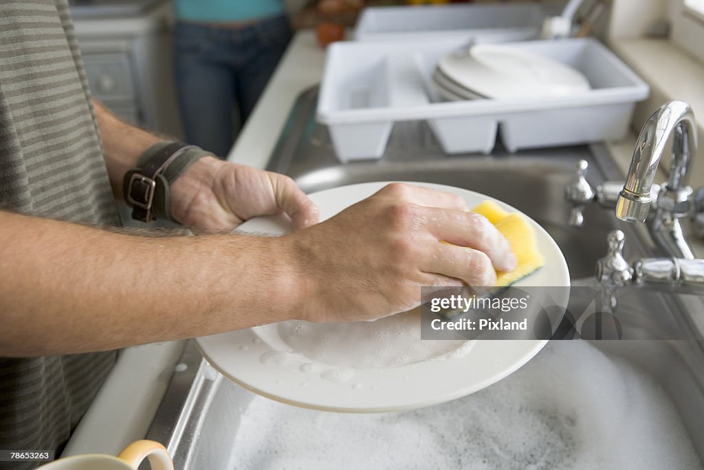Person's hands washing dishes