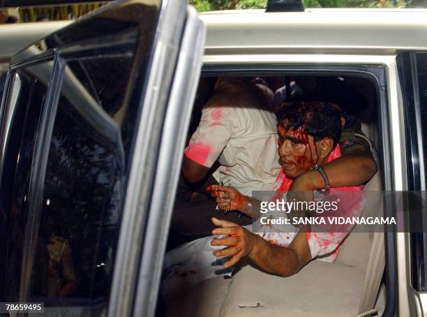 Battered and bruised Sri Lanka's Labour Minister Mervin Silva tries to close the door of his vehicle, while a policeman puts his arm around him...