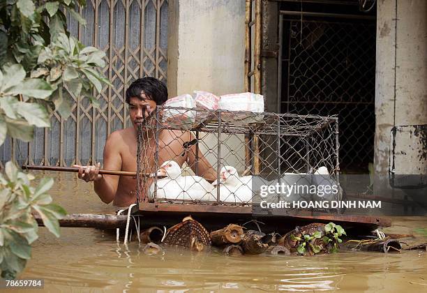 Man leaves his flooded house with a cage of ducks in the Thach Thanh district, in the central province of Thanh Hoa, 08 October 2007. Some 58 people...