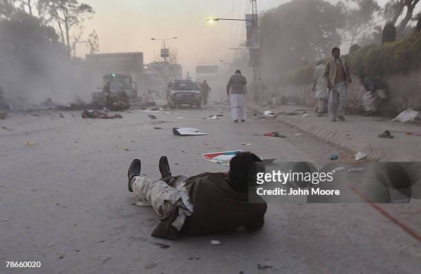 Wounded man looks towards the site of a bomb attack on former Prime Minister Benazir Bhutto on December 27, 2007 in Rawalpindi, Pakistan. The...