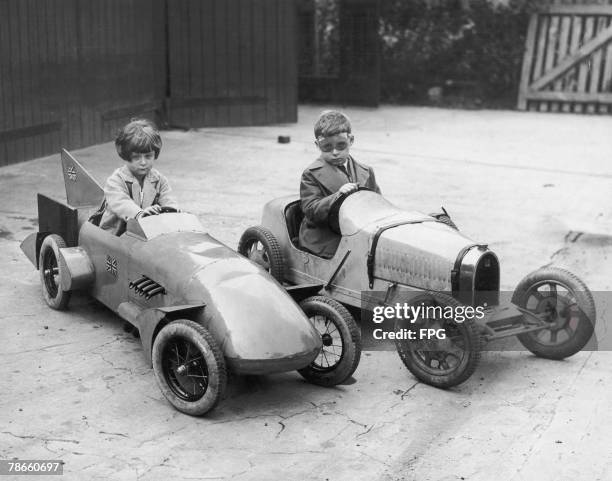 Jean and Donald Campbell , children of English racing driver Sir Malcolm Campbell, in their toy cars at home in Horley, Surrey, circa 1930. Jean is...