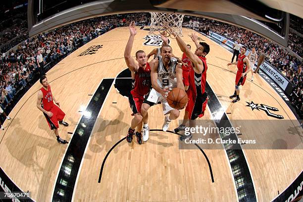Tony Parker of the San Antonio Spurs shoots against Kris Humphries and Jason Kapono of the Toronto Raptors at the AT&T Center December 28, 2007 in...