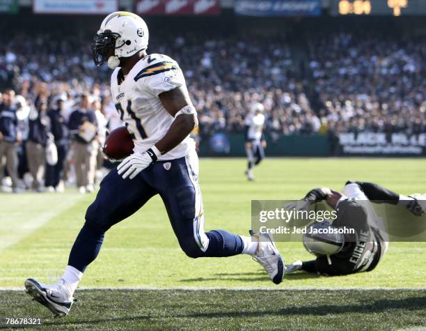 LaDainian Tomlinson of the San Diego Chargers runs for a touchdown past Hiram Eugene of the Oakland Raiders during the first quarter of an NFL game...