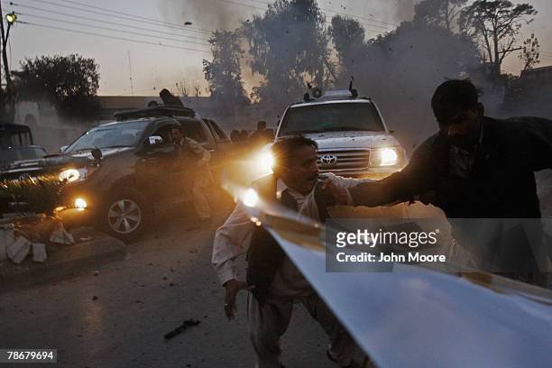 Survivors of a suicide bomb attack scramble to get out of the way as the vehicle , of slain former Prime Minister Benazir Bhutto speeds away from the...