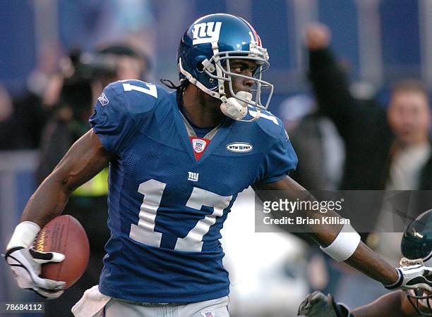 New York Giants wide receiver Plaxico Burress stiff-arms a Philadelphia Eagles defender on his way to the end zone at Giants Stadium in East...