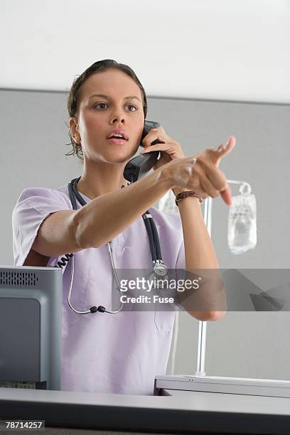 physician pointing while on telephone - multitasking nurse stock pictures, royalty-free photos & images
