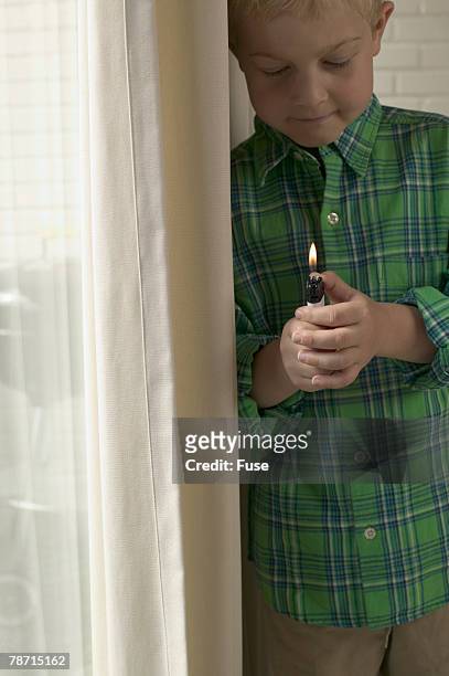 boy playing with lighter by curtains - green lighter stock pictures, royalty-free photos & images