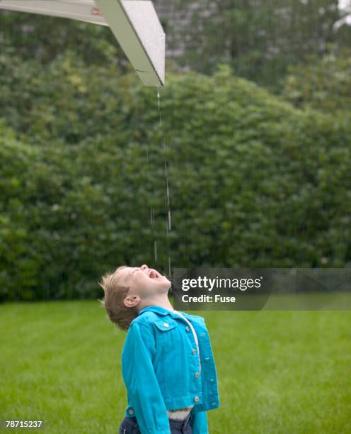 boy catching raindrops from eaves in his mouth - catching stock pictures, royalty-free photos & images
