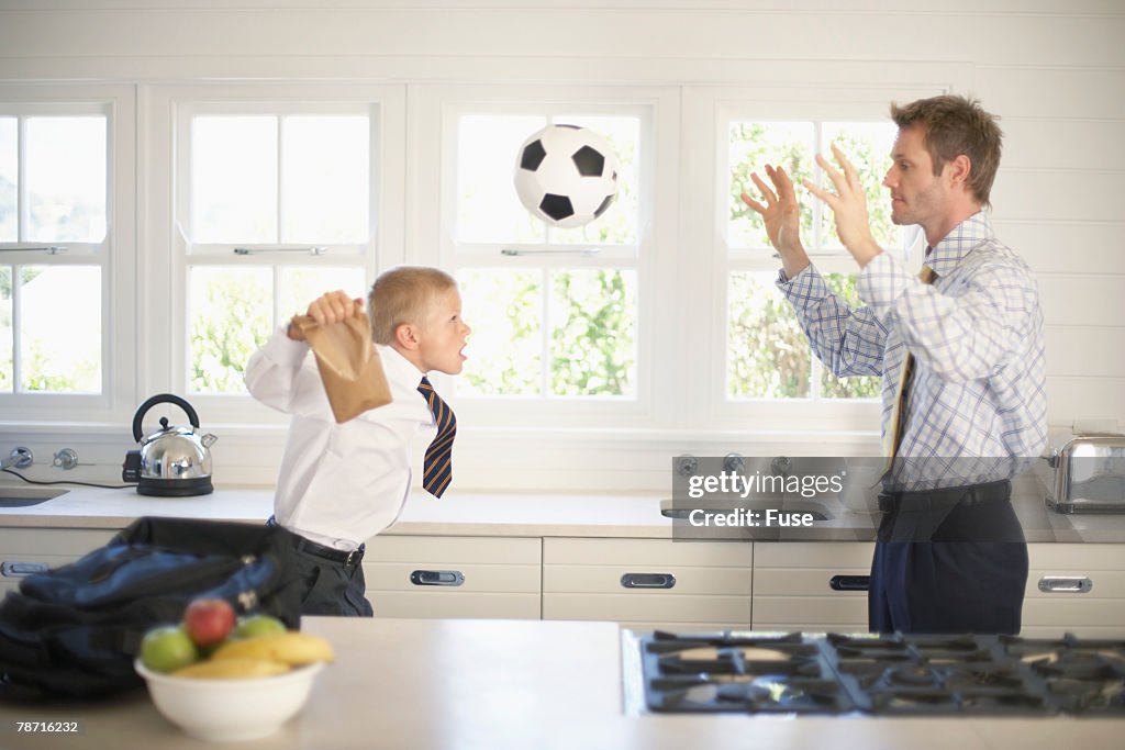 Father and Son Playing with a Soccer Ball in Kitchen