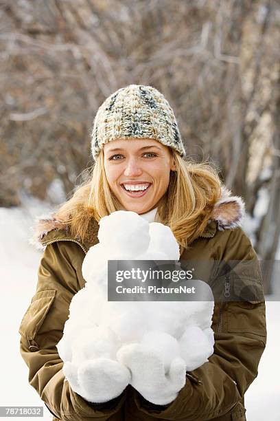 smiling woman holding pile of snowballs - snowball pile stock pictures, royalty-free photos & images