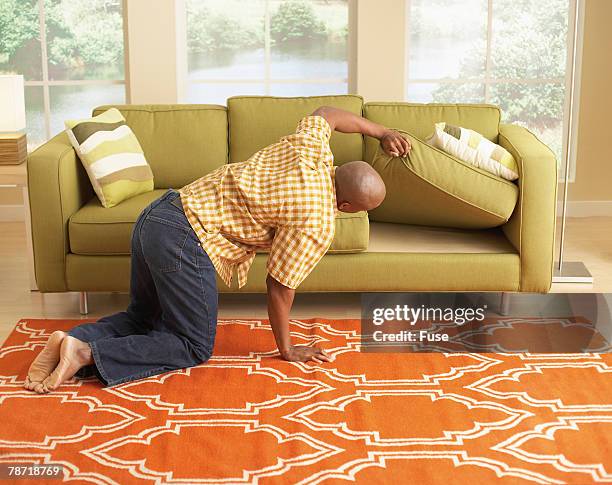 man searching under the couch cushions - cushion imagens e fotografias de stock