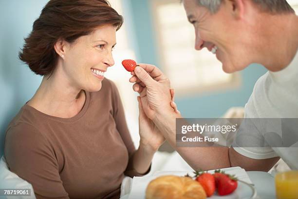 man feeding woman breakfast in bed - verführung stock-fotos und bilder