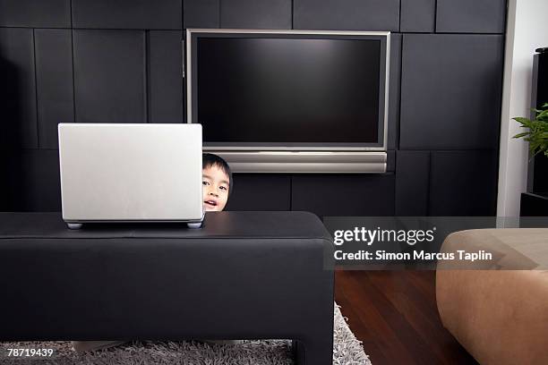 boy peering behind laptop - hiding behind laptop stock pictures, royalty-free photos & images