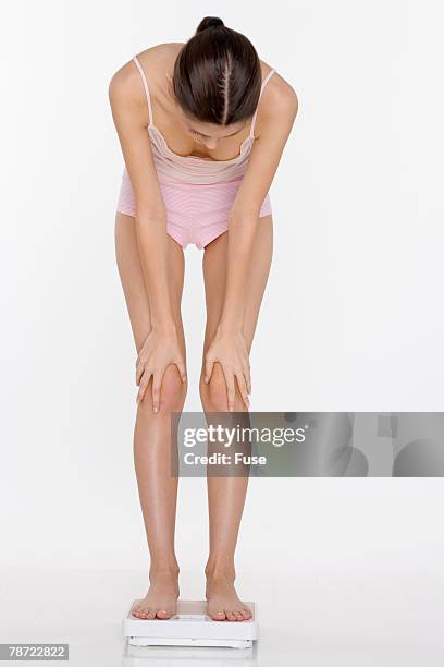young woman on scale - hand on knee stock pictures, royalty-free photos & images