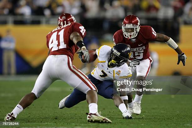 Noel Devine of the West Virginia Mountaineers tries to elude Darien Williams and Dominique Franks of the Oklahoma Sooners after gaining 13-yards on a...