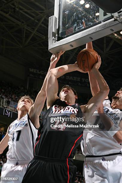 Jason Smith of the Philadelphia 76ers goes up for the shot against Andrei Kirilenko and Mehmet Okur of the Utah Jazz at EnergySolutions Arena on...