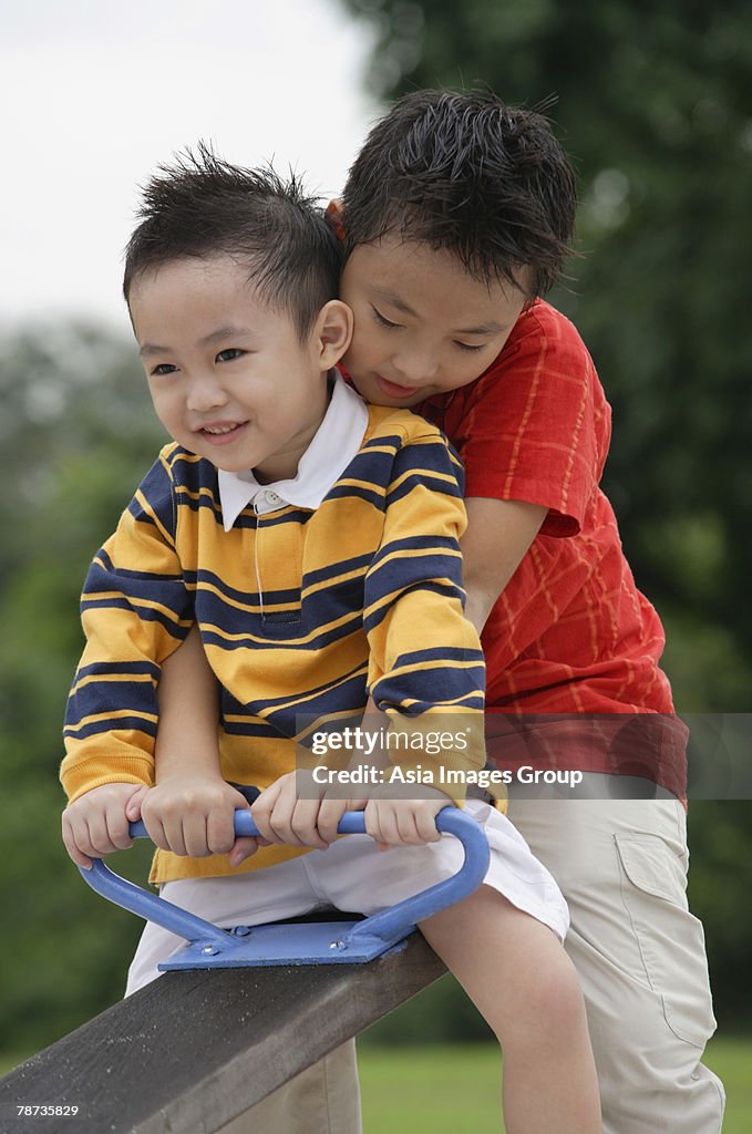 Two brothers sitting on See-Saw