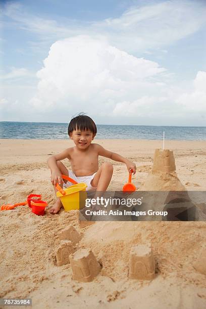 young boy on beach building sand castle, smiling - hot boy body stock pictures, royalty-free photos & images