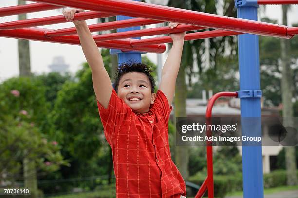 boy using the jungle gym at playground - boy on monkey bars stock pictures, royalty-free photos & images