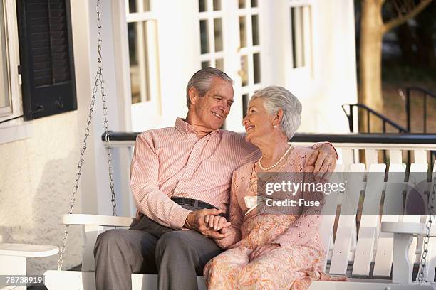 senior couple together on their porch - hollywoodschaukel stock-fotos und bilder