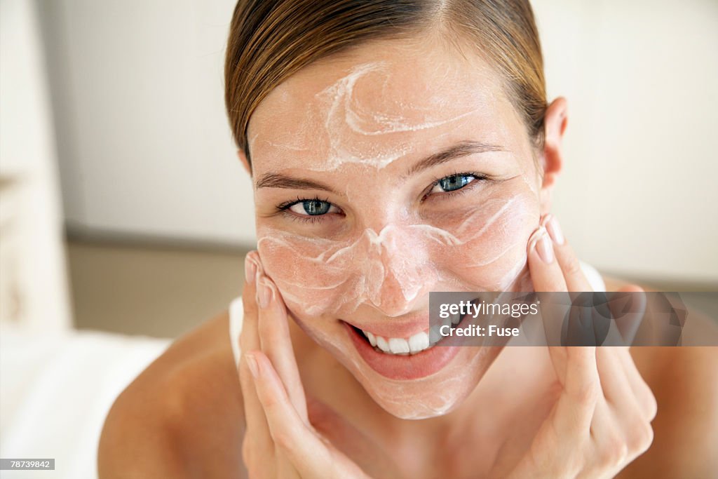 Smiling Young Woman Applying Face Cream
