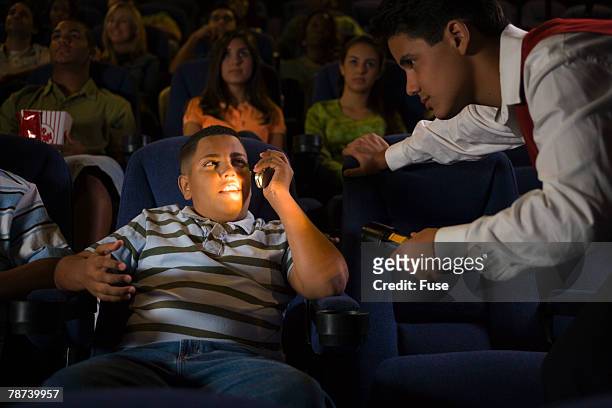 kid using cell phone at the movies - acomodador cine fotografías e imágenes de stock