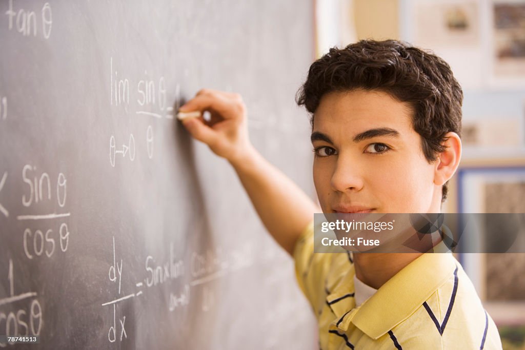 High School Student Writing Equation on Chalkboard