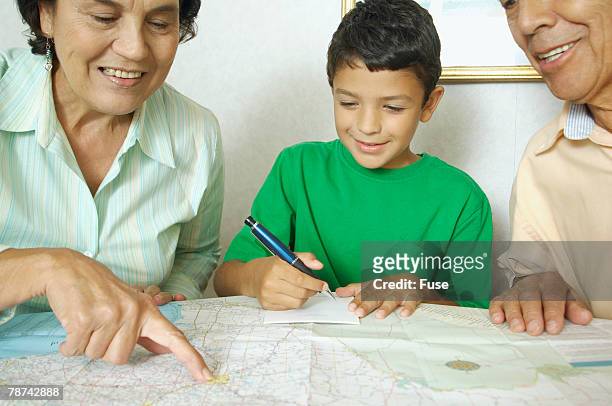 grandparents and boy reading map - orientierungslauf landkarte gruppe stock-fotos und bilder