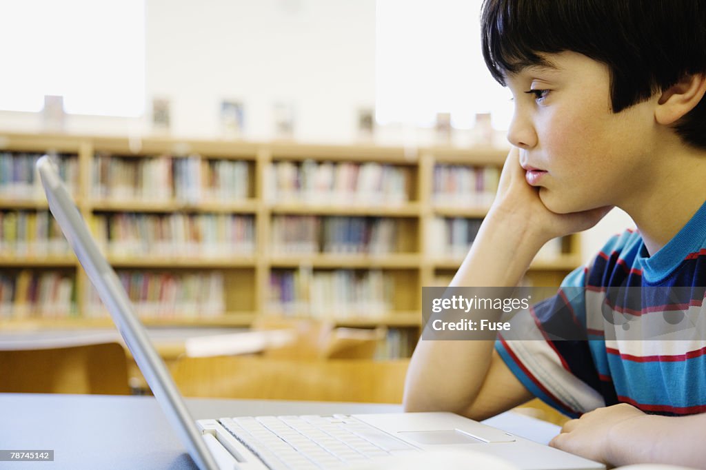 Boy in Library Looking at Laptop