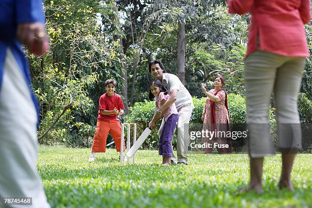 family playing cricket in park - family cricket stockfoto's en -beelden