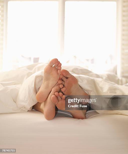 feet of two lovers in bed - playing footsie stock pictures, royalty-free photos & images