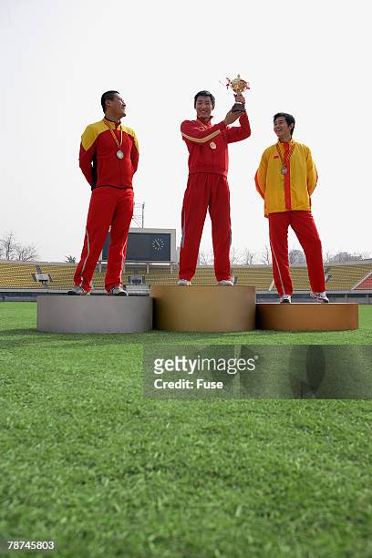 athletes standing on winner s podium - winners podium people stock pictures, royalty-free photos & images