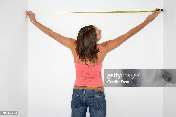 young woman measuring wall - mujeres de mediana edad fotografías e imágenes de stock