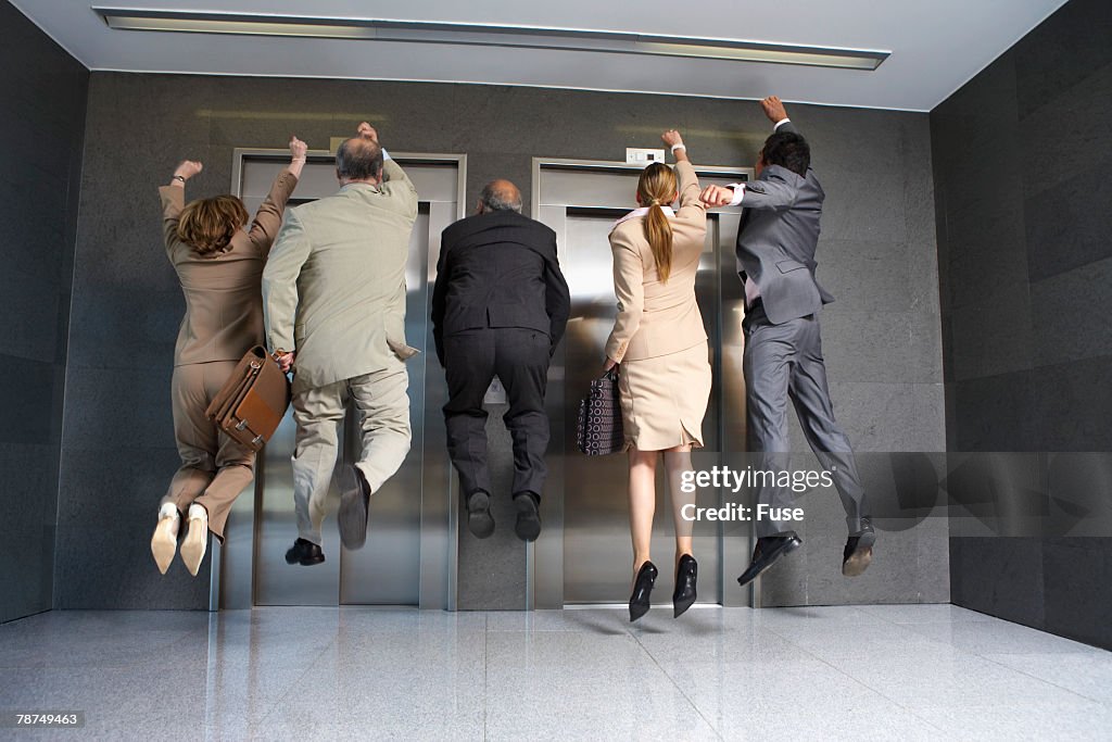 Business People Jumping in Front of Elevator