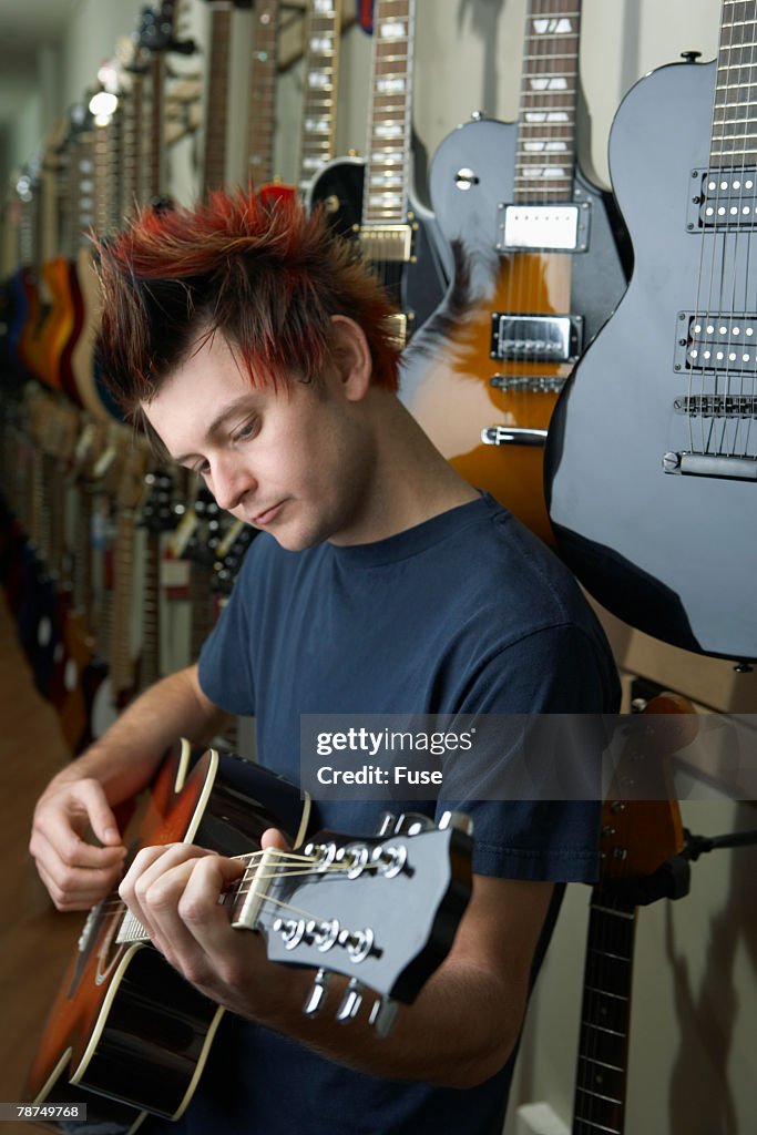 Young Man Playing Guitar in Music Store