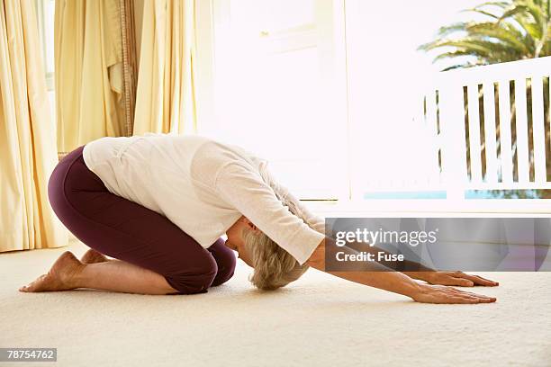 middle-aged woman stretching on floor - yoga rug stock pictures, royalty-free photos & images