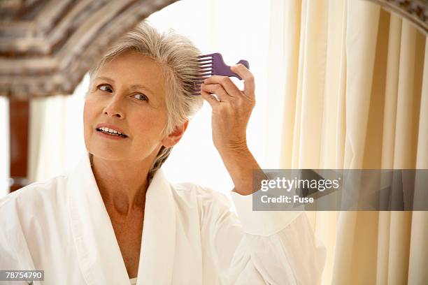middle-aged woman combing hair - woman brushing hair stockfoto's en -beelden