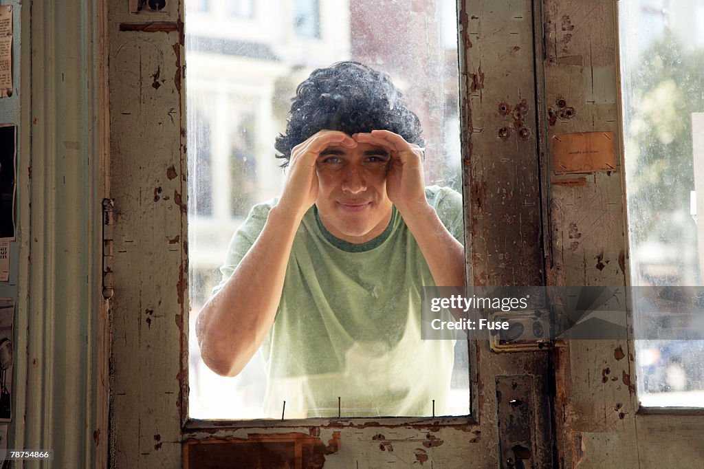 Man Peering Through Window of Closed Store