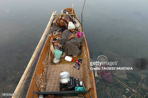 Kashmiri Muslim warms his son inside his traditional gown on a boat moored on Dal Lake in Srinagar, 04 January 2007. The Kashmir valley is reeling...