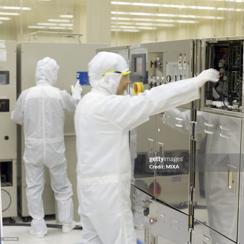 A technician in white lab suit checking machine