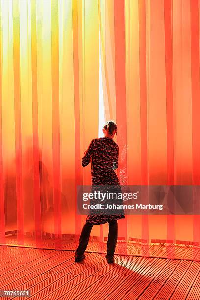 rear view of a woman in front of a red curtain - red curtain stockfoto's en -beelden