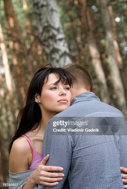 a couple embracing in the woods - female looking away from camera serious thinking outside natural stock pictures, royalty-free photos & images