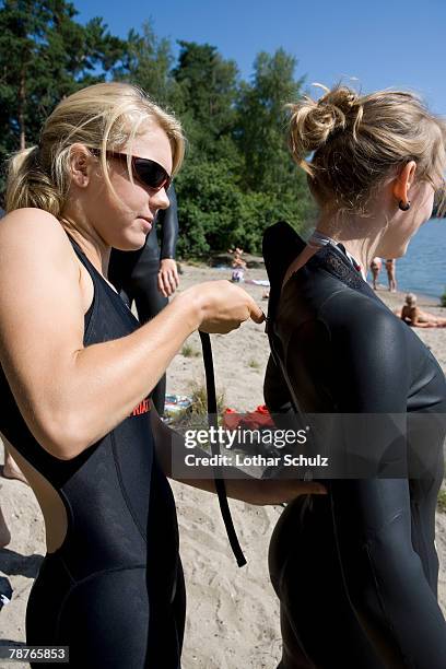 a woman fastening her friend's wetsuit - wetsuit stock pictures, royalty-free photos & images